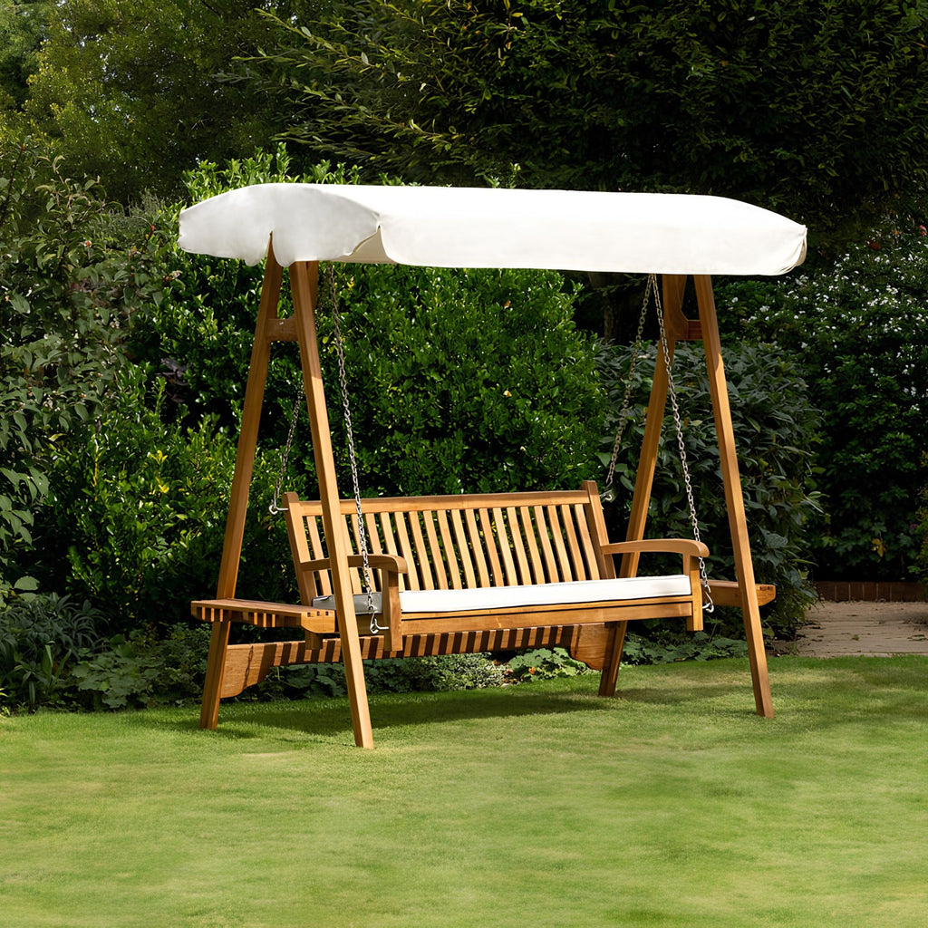 Chic Teak wooden garden swing seat with cream canopy on a lawn in a landscaped garden