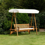 Chic Teak wooden garden swing seat with cream canopy on a lawn in a landscaped garden